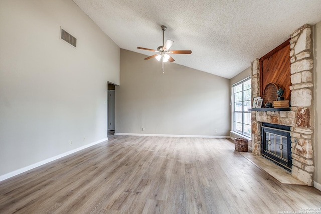 3030 Heidi St, San Antonio, TX 78247 - unfurnished living room with a ceiling fan, a stone fireplace, a textured ceiling, lofted ceiling, and light wood finished floors