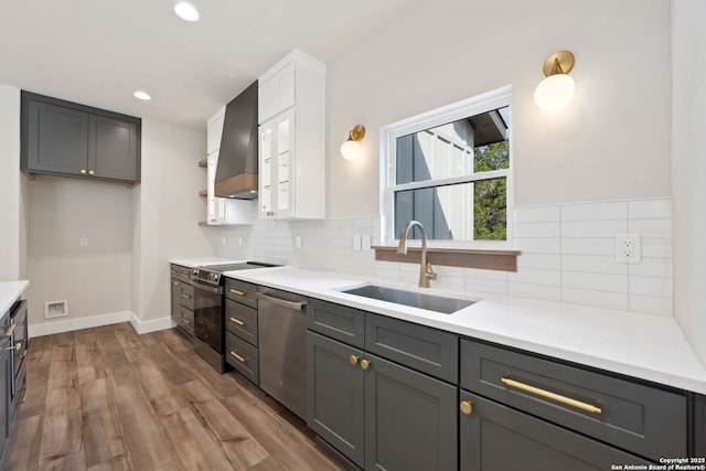 604 Compass Rose, Canyon Lake, TX 78133 - kitchen with appliances with stainless steel finishes, wall chimney exhaust hood, a sink, wood finished floors, and tasteful backsplash