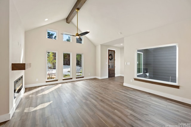 604 Compass Rose, Canyon Lake, TX 78133 - unfurnished living room with ceiling fan, a glass covered fireplace, beam ceiling, wood finished floors, and baseboards