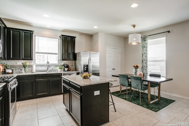 9910 Cowboy Ln, San Antonio, TX 78254 - kitchen with stainless steel appliances, dark cabinetry, tasteful backsplash, a kitchen island, and light stone countertops
