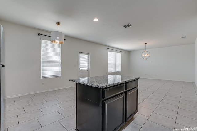 9910 Cowboy Ln, San Antonio, TX 78254 - kitchen featuring light tile patterned flooring, stone counters, dark cabinetry, a kitchen island, and pendant lighting