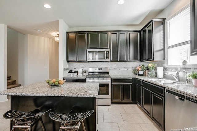 9910 Cowboy Ln, San Antonio, TX 78254 - kitchen featuring stainless steel appliances, a sink, light tile patterned floors, backsplash, and light stone counters