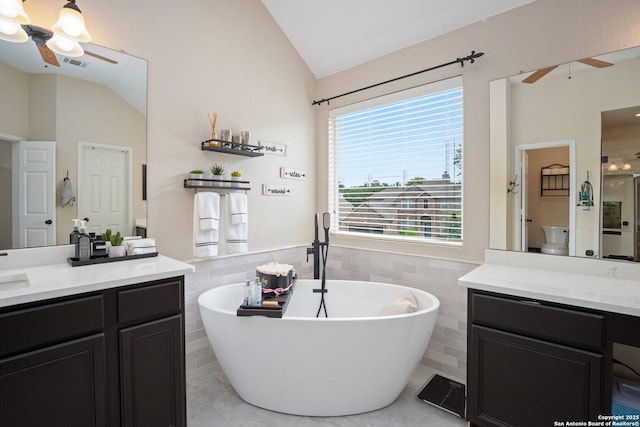 19426 Desert Oak, San Antonio, TX 78258 - full bathroom featuring a ceiling fan, lofted ceiling, tile walls, vanity, and a freestanding bath