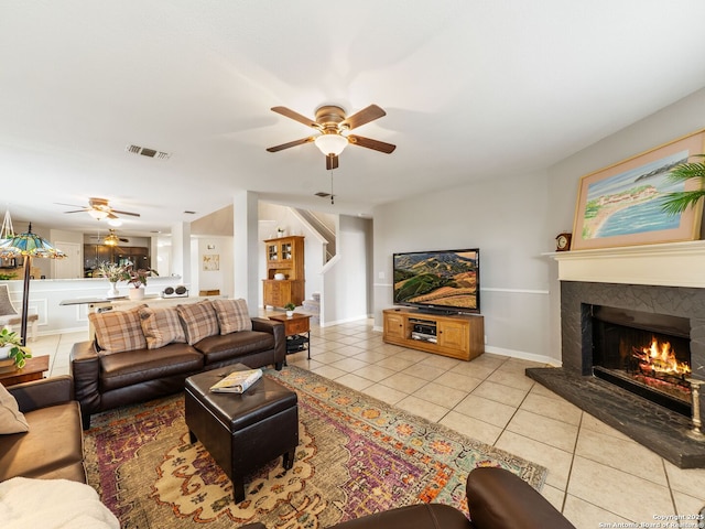 3842 Fiesta Trl, San Antonio, TX 78245 - living room featuring ceiling fan, light tile patterned floors, a warm lit fireplace, and stairs
