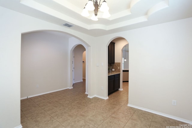 1415 Crane Ct, San Antonio, TX 78245 - empty room with a tray ceiling, a chandelier, light tile patterned flooring, arched walkways, and baseboards