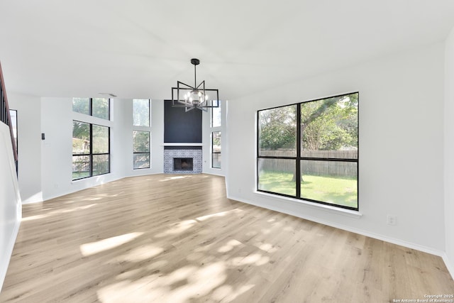 16415 Old Stable, San Antonio, TX 78247 - unfurnished living room featuring a chandelier, light wood-style flooring, baseboards, and a fireplace