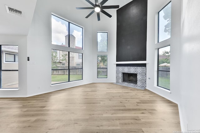 16415 Old Stable, San Antonio, TX 78247 - unfurnished living room featuring a high ceiling, ceiling fan, wood finished floors, a tiled fireplace, and baseboards