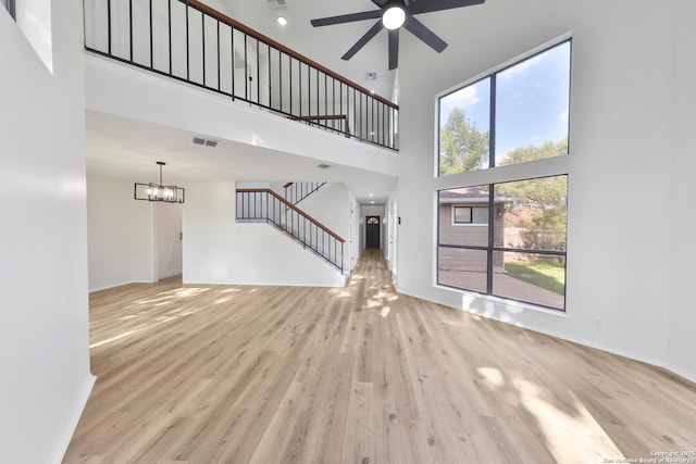 16415 Old Stable, San Antonio, TX 78247 - unfurnished living room featuring a high ceiling, stairway, wood finished floors, ceiling fan, and a chandelier