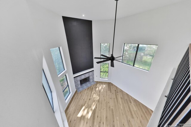 16415 Old Stable, San Antonio, TX 78247 - unfurnished living room featuring a towering ceiling, a fireplace, wood finished floors, healthy amount of natural light, and a ceiling fan