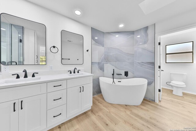 16415 Old Stable, San Antonio, TX 78247 - bathroom featuring double vanity, wood finished floors, a freestanding tub, toilet, and recessed lighting