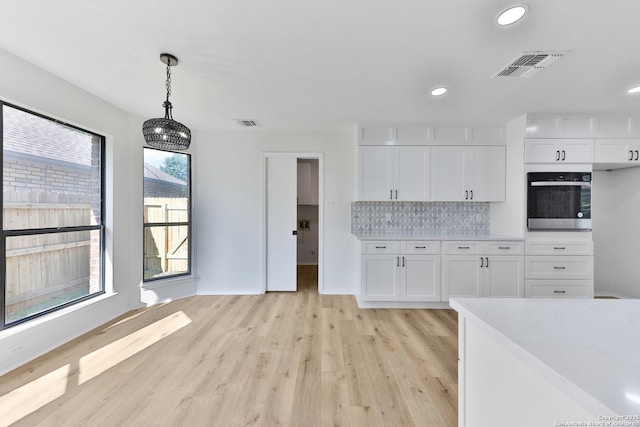 16415 Old Stable, San Antonio, TX 78247 - kitchen with oven, light wood-style floors, white cabinets, light countertops, and pendant lighting
