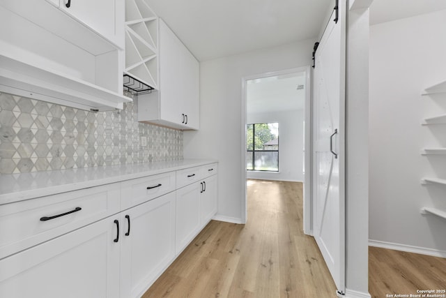 16415 Old Stable, San Antonio, TX 78247 - kitchen featuring open shelves, a barn door, light wood-type flooring, and tasteful backsplash