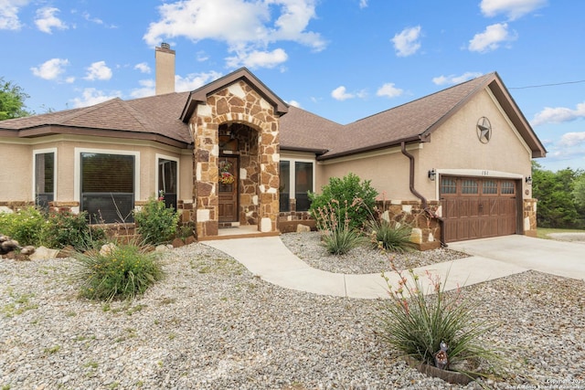 151 Native Pecan, Canyon Lake, TX 78133 - view of front of house with stone siding, a garage, a chimney, driveway, and stucco siding