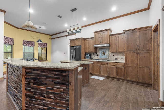 151 Native Pecan, Canyon Lake, TX 78133 - kitchen with stainless steel appliances, a center island with sink, under cabinet range hood, dark wood-style flooring, and decorative backsplash