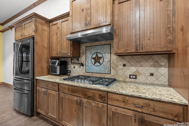 151 Native Pecan, Canyon Lake, TX 78133 - kitchen with stainless steel appliances, under cabinet range hood, crown molding, backsplash, and wood finished floors
