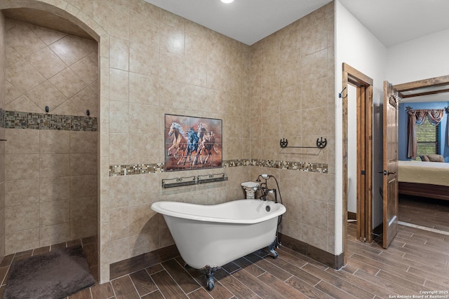 151 Native Pecan, Canyon Lake, TX 78133 - full bathroom featuring connected bathroom, a freestanding tub, wood finish floors, tile walls, and a walk in shower