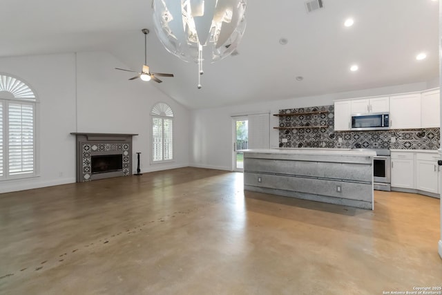 942 Lightstone, San Antonio, TX 78258 - kitchen featuring stainless steel appliances, high vaulted ceiling, white cabinets, a fireplace, and backsplash