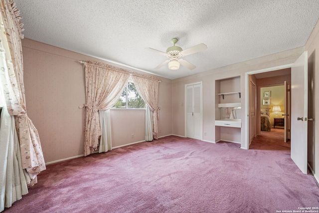 11 El Norte Cir, Uvalde, TX 78801 - unfurnished bedroom with carpet floors, a textured ceiling, a closet, baseboards, and a ceiling fan