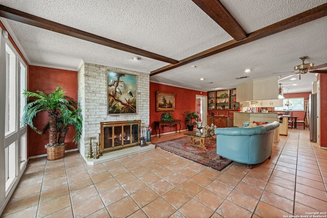 11 El Norte Cir, Uvalde, TX 78801 - living room featuring a textured ceiling, a brick fireplace, beamed ceiling, light tile patterned floors, and ceiling fan