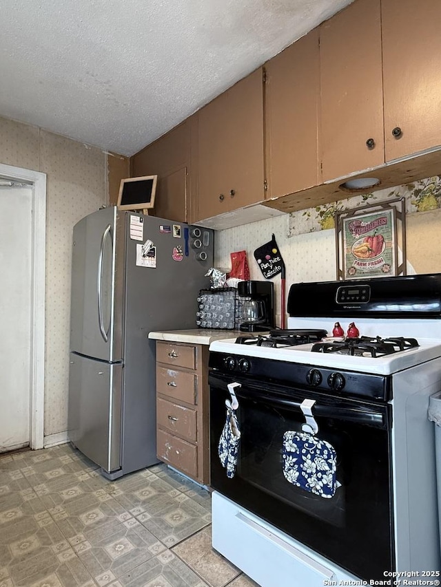 2407 Aiken, San Antonio, TX 78237 - kitchen featuring gas range, light countertops, freestanding refrigerator, and a textured ceiling