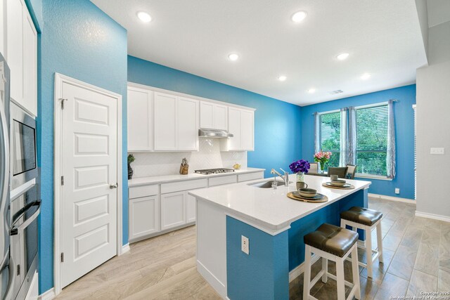 1524 Leeds Park, Bulverde, TX 78163 - kitchen with a sink, a breakfast bar, an island with sink, under cabinet range hood, and stainless steel appliances
