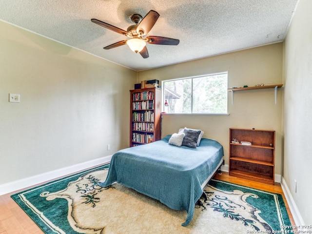 6802 S Forest Hvn, San Antonio, TX 78240 - bedroom with wood finished floors, a textured ceiling, a ceiling fan, and baseboards