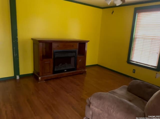 726 Ave L, Poteet, TX 78065 - living area with dark wood-type flooring, a fireplace, baseboards, ceiling fan, and crown molding