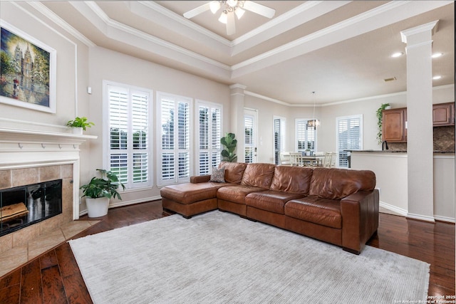 21910 Barton Woods, San Antonio, TX 78259 - living room featuring ornate columns, dark wood-style floors, crown molding, ceiling fan, and a tiled fireplace