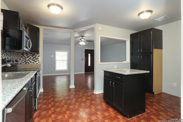 772 Cresthill, San Antonio, TX 78220 - kitchen with stainless steel appliances, dark cabinets, a ceiling fan, tasteful backsplash, and light stone counters