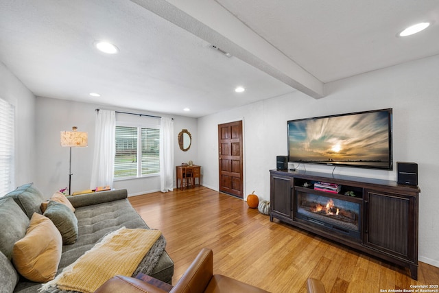 1119 N Pine St, San Antonio, TX 78202 - living room featuring light wood-type flooring, recessed lighting, beam ceiling, a glass covered fireplace, and baseboards