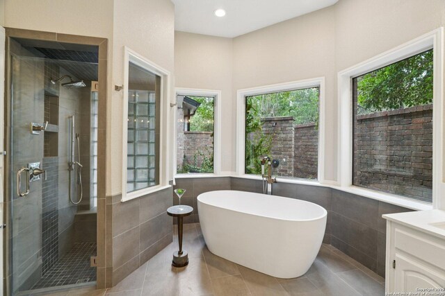 21641 Forest Waters, Garden Ridge, TX 78266 - bathroom featuring tile walls, a stall shower, a soaking tub, healthy amount of natural light, and vanity