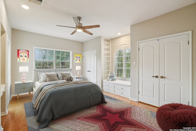 21641 Forest Waters, Garden Ridge, TX 78266 - bedroom featuring multiple closets, multiple windows, light wood finished floors, a ceiling fan, and recessed lighting