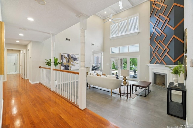 21641 Forest Waters, Garden Ridge, TX 78266 - living room with a ceiling fan, ornate columns, a fireplace, wood finished floors, and a high ceiling