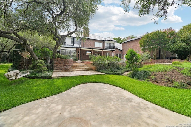 21641 Forest Waters, Garden Ridge, TX 78266 - rear view of property with a standing seam roof, a lawn, brick siding, metal roof, and a balcony