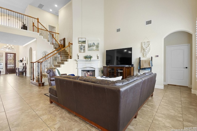 9718 Rosemire Way, San Antonio, TX 78254 - living area with arched walkways, a high ceiling, stairs, light tile patterned flooring, and a fireplace