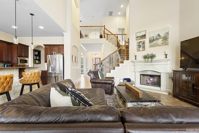 9718 Rosemire Way, San Antonio, TX 78254 - living room featuring arched walkways, a towering ceiling, stairway, a premium fireplace, and ornamental molding