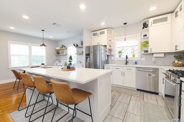 203 Rehmann, San Antonio, TX 78204 - kitchen with open shelves, appliances with stainless steel finishes, a center island, backsplash, and white cabinets
