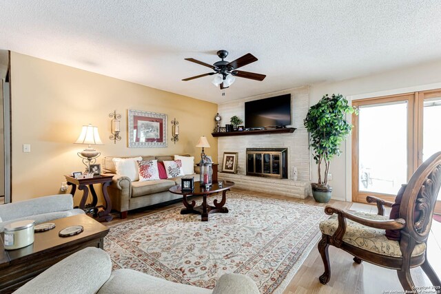 16519 Burr Hill, San Antonio, TX 78247 - living room featuring wood finished floors, a textured ceiling, ceiling fan, and a brick fireplace