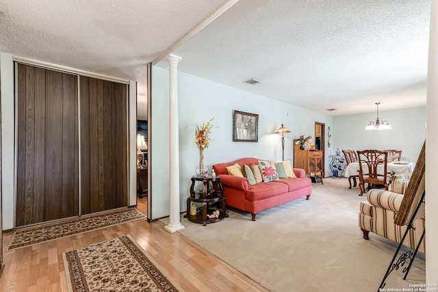 16519 Burr Hill, San Antonio, TX 78247 - living room featuring a textured ceiling, decorative columns, light wood-style floors, and a chandelier