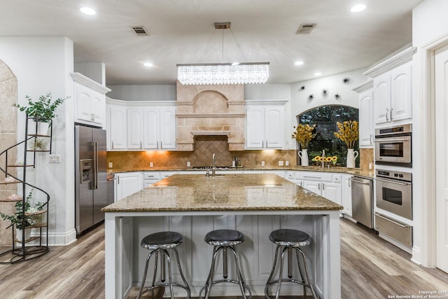 10 Kings Tower, San Antonio, TX 78257 - kitchen featuring appliances with stainless steel finishes, a warming drawer, light wood-type flooring, light stone countertops, and a breakfast bar area