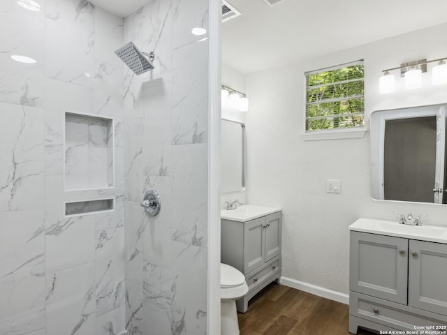 942 San Angelo, San Antonio, TX 78201 - full bathroom featuring wood finished floors, two vanities, a marble finish shower, baseboards, and toilet
