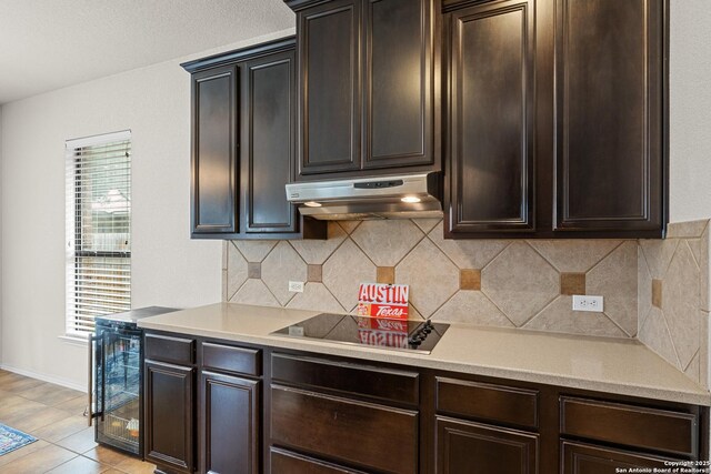 9815 Leubeck Rnch, Helotes, TX 78023 - kitchen with under cabinet range hood, black electric stovetop, wine cooler, and dark brown cabinetry