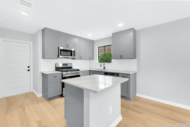 9807 Boulder Hill, San Antonio, TX 78250 - kitchen with gray cabinetry, stainless steel appliances, a sink, light wood-style flooring, and tasteful backsplash