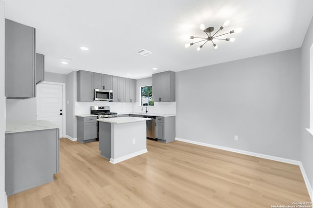 9807 Boulder Hill, San Antonio, TX 78250 - kitchen featuring appliances with stainless steel finishes, gray cabinets, light wood-style floors, a chandelier, and recessed lighting