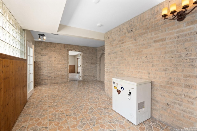 585 Oak Bend Dr, Bandera, TX 78003 - empty room featuring brick wall, arched walkways, light stone finish floors, and a smoke detector