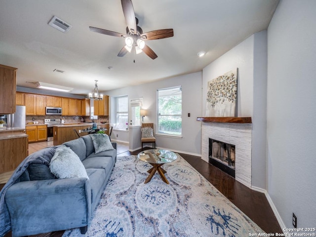 520 Foxford Run Dr, Schertz, TX 78108 - living area with baseboards, ceiling fan, a stone fireplace, wood finished floors, and a chandelier