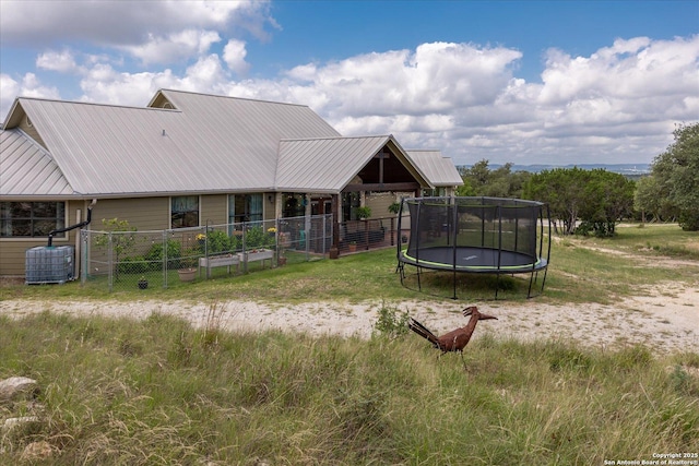 122 Twisting Oaks Ct, Pipe Creek, TX 78063 - rear view of property with a trampoline, metal roof, and central AC