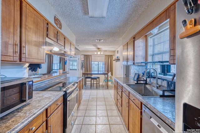 105 S Bluebonnet, Uvalde, TX 78801 - kitchen with stainless steel appliances, a sink, a textured ceiling, under cabinet range hood, and brown cabinetry