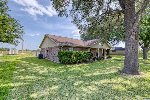 105 S Bluebonnet, Uvalde, TX 78801 - view of front of home with brick siding, a front yard, central AC, and a shingled roof
