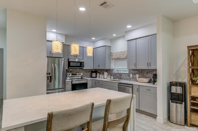 524 Flaman, Canyon Lake, TX 78133 - kitchen featuring appliances with stainless steel finishes, gray cabinetry, tasteful backsplash, light wood-style flooring, and hanging light fixtures